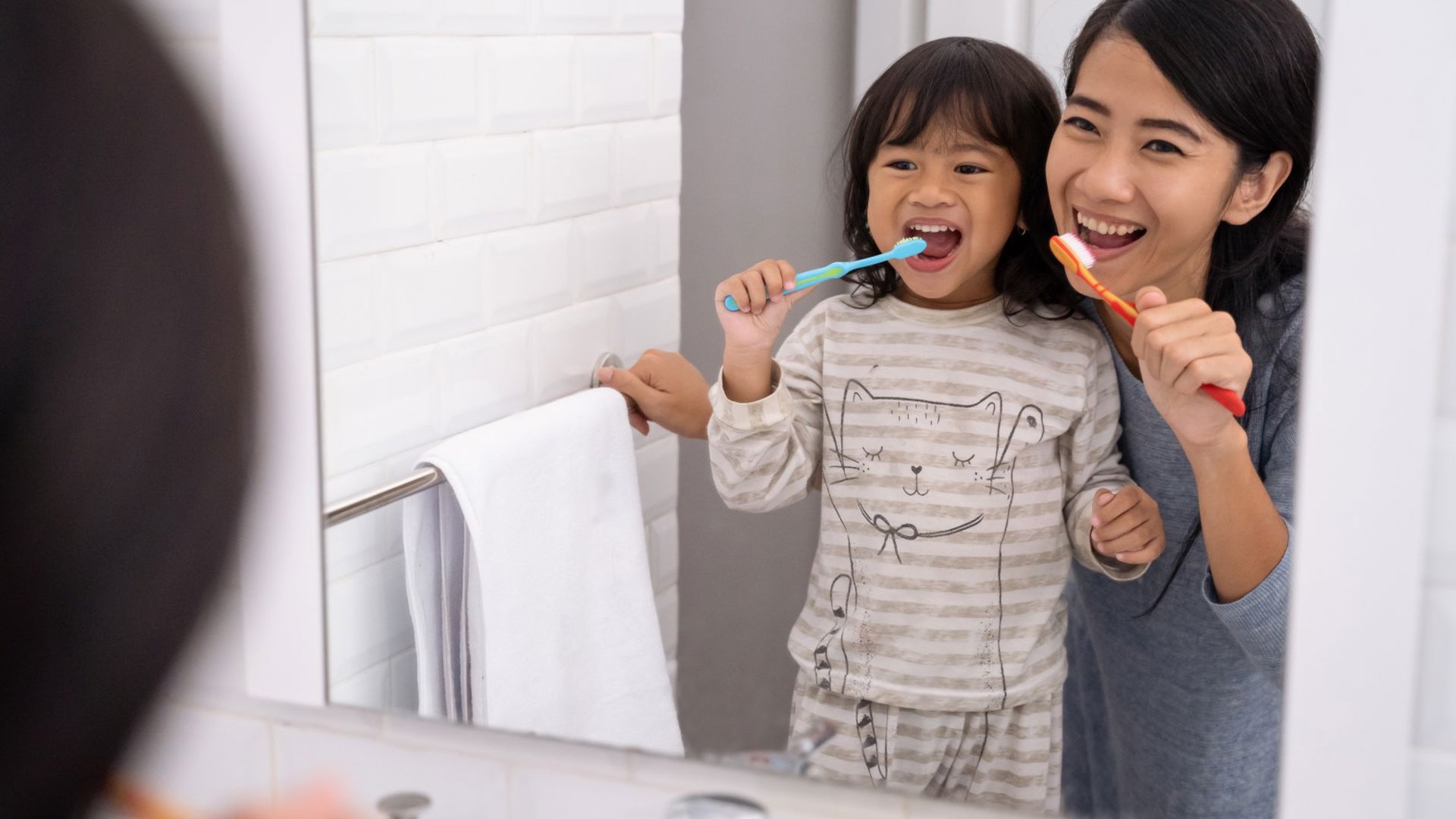 Mother and daughter brushing teeth