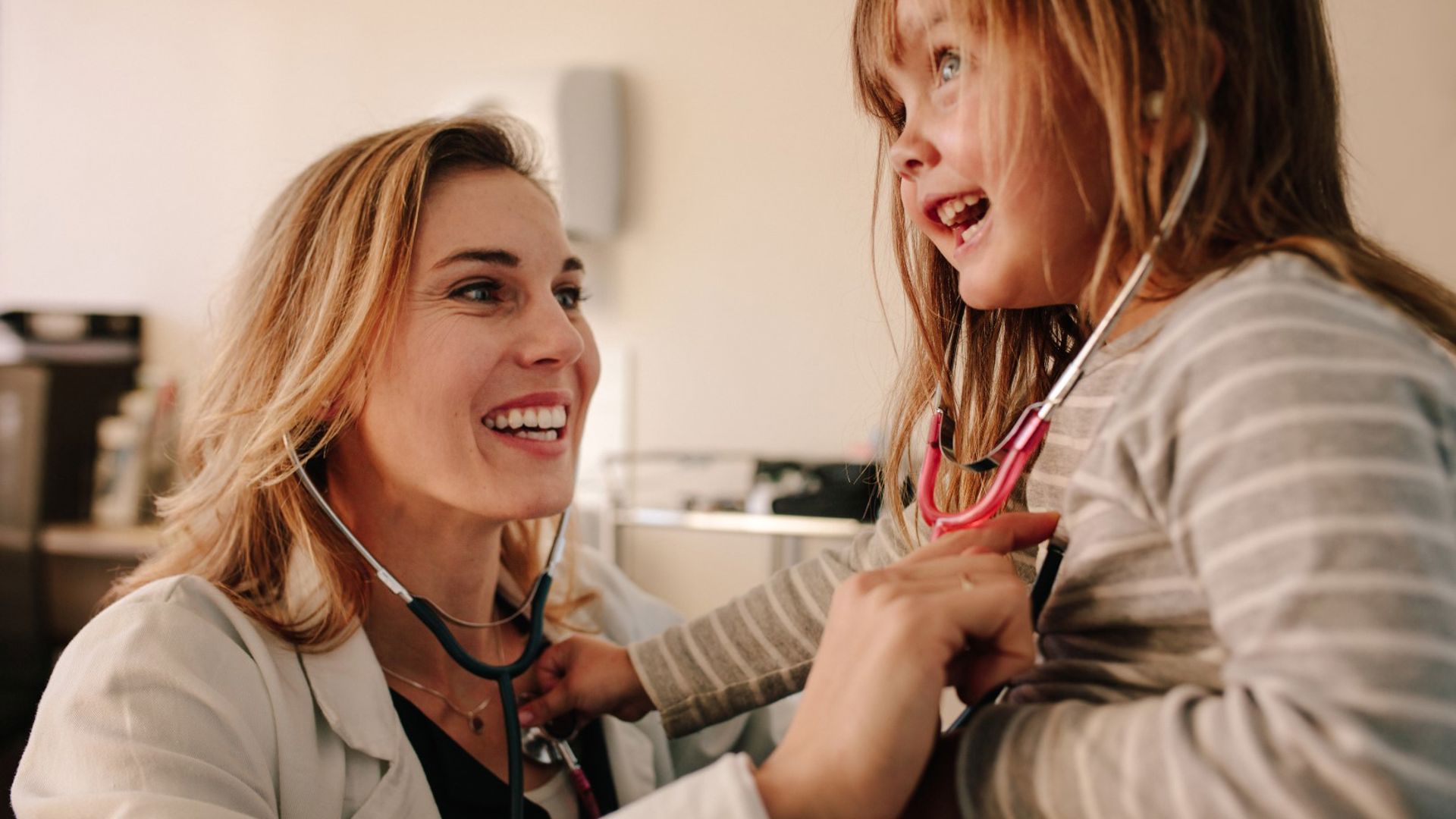 A doctor listening to a child's heartbeat, being getting surgery using their private health insurance