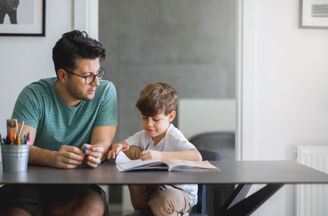 Young father with glasses doing homework with his son