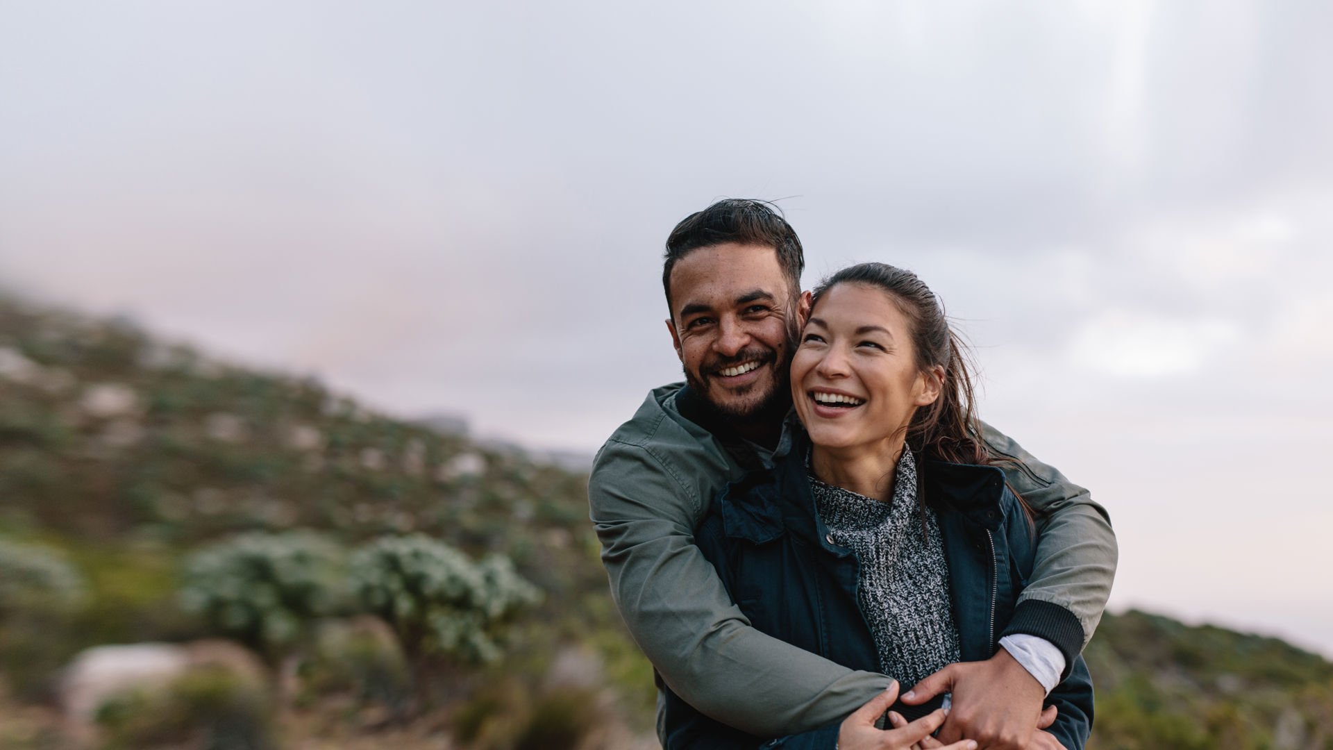 Young couple cuddling outside looking happy