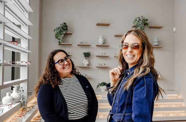 Customer visiting GMHBA Eye Care trying on a new pair of green glasses