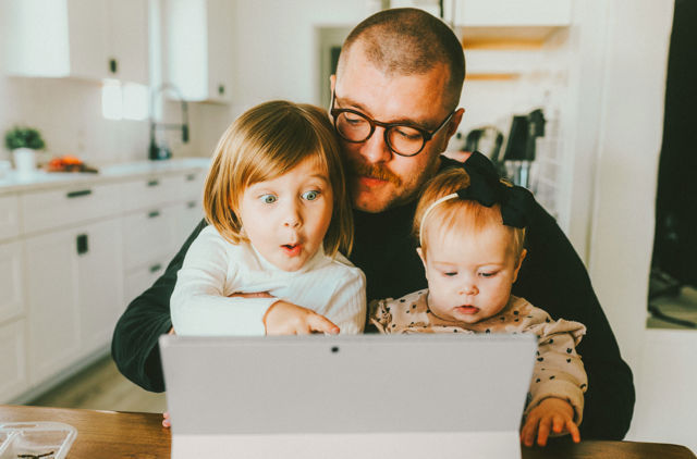 Dad on Laptop looking at health insurance with children on lap