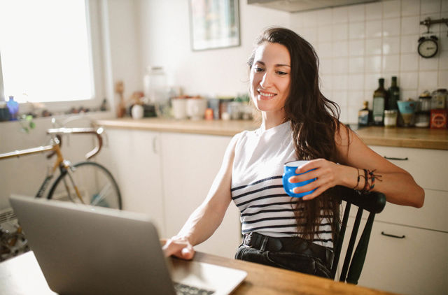 female enjoying a coffee in her kitchen researching health insurance