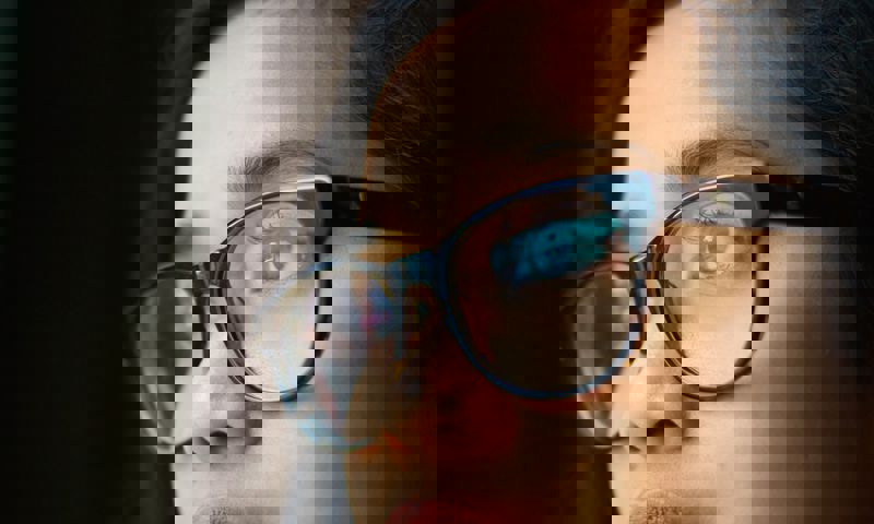 Kid on device with reflection in glasses